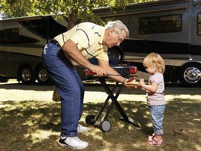 Grandfather BBQing with child at an RV stop